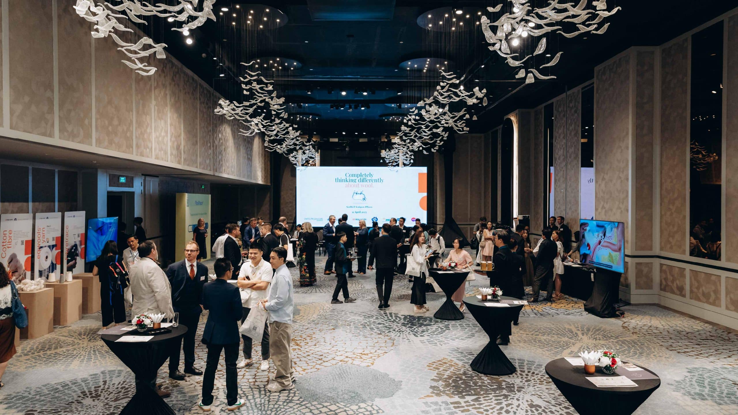 The Vietnam conference room showing the presentation screen with people networking in front of it.